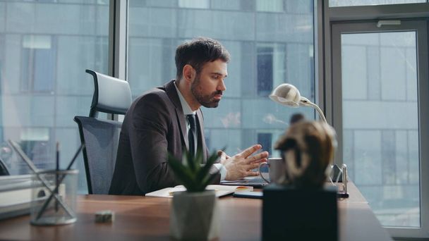 Vállalkozó megvitatása munka online konferencia ülés irodai asztal közelről. Magabiztos szakállas férfi menedzser néz laptop kamera miután videohívás. Elfoglalt üzletember beszél az internetes találkozón. - Fotó, kép