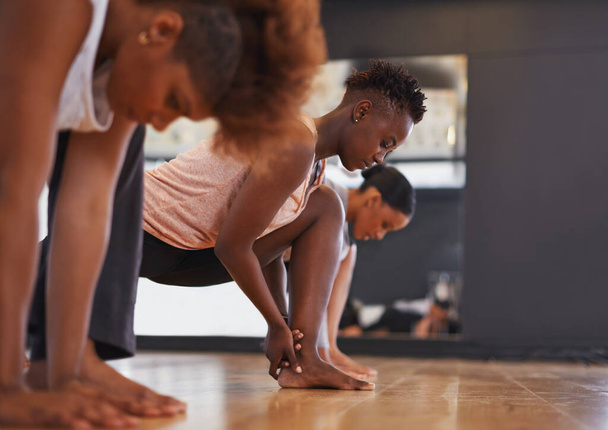 Dancer, group and stretching legs in studio for workout, exercise or vision for wellness with muscle. People, friends and dancing team in warm up, start or together for class, art and ballet on floor. - Photo, Image