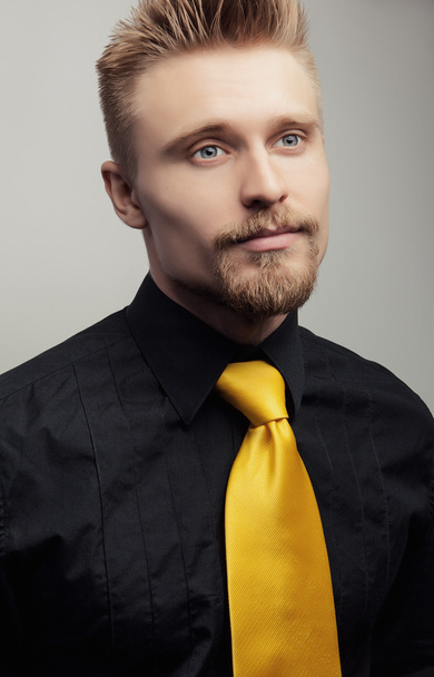 Elegante jonge knappe man in zwarte shirt & gele stropdas. Studio mode portret. - Foto, afbeelding