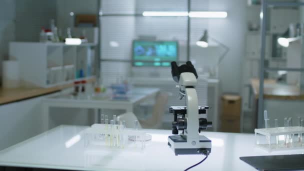 Nessun colpo della gente del microscopio e delle provette di vetro negli scaffali dello stand sulla tabella bianca nel laboratorio scientifico moderno - Filmati, video