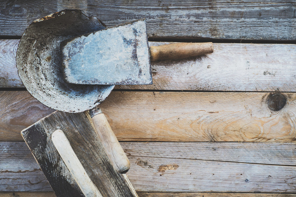 Conjunto de ferramentas de alvenaria usadas antigas em uma superfície de madeira áspera
 - Foto, Imagem