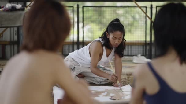 Una mujer arrodillada captura a dos mujeres sobre lienzo - 4K Concepto artístico - Metraje, vídeo