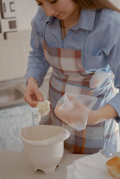 Una pastelera femenina prepara glaseado para magdalenas. Disfrute del arte de hornear en casa con este chef de pastelería casero elaborando deliciosas golosinas en casa. - Foto, imagen