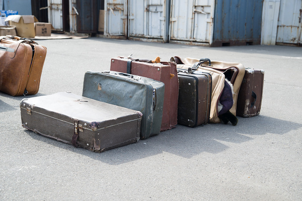 Verschillende oude koffers kleren zijn op asfalt. - Foto, afbeelding