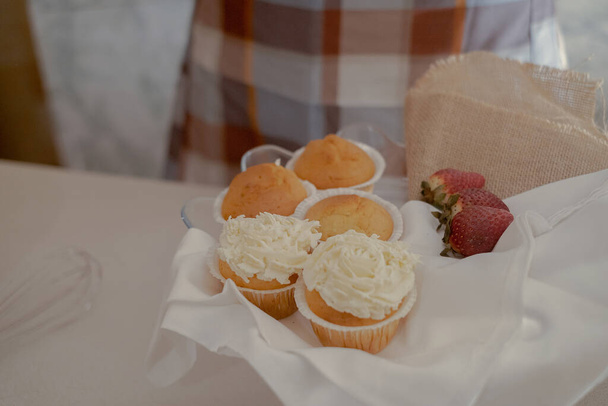 Na mesa estão cupcakes, mostrando a arte de um padeiro de pastelaria. A mesa da cozinha exibe as ferramentas e ingredientes de um chef de pastelaria, pronto para criações culinárias. - Foto, Imagem