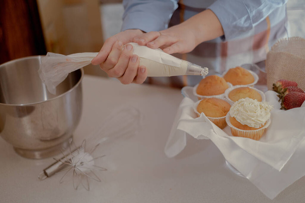 Naaras kondiittori putket kuorrutus päälle cupcakes, esittelee kotitekoinen leivonnaisia. Tutustu kodin leivonnan ja pienimuotoisen liiketoiminnan viehätykseen tämän kuvan ammattitaitoisesta leipurista työssä. - Valokuva, kuva