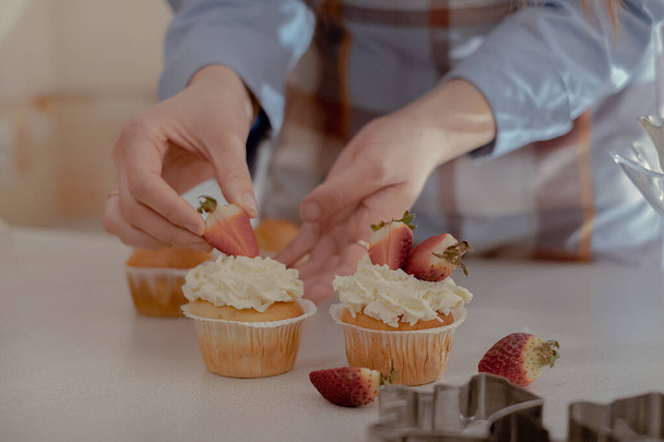 Egy női cukrász bogyókkal díszíti a muffinokat, bemutatva a házi készítésű süteményeit. Fedezze fel a varázsa otthoni sütés és a kis léptékű üzleti ezzel a képpel egy képzett pék a munkahelyen. - Fotó, kép