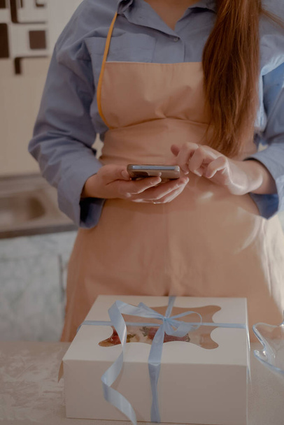 Naispuolinen kokki-kondiittori ottaa kuvia matkapuhelimellaan mainostaakseen liiketoimintaansa, korostaen kotitekoista leivontaa. Koe ydin pienimuotoisen, ympäristöystävällisen paistaminen gluteenittomia ja sokerittomia tuotteita, edistää terveellistä ruokavaliota. - Valokuva, kuva