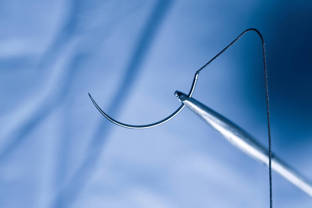 Foto de primer plano de un soporte de aguja y aguja de medio círculo con sutura durante la operación. - Foto, imagen