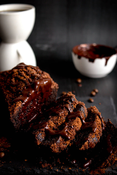 Gâteau au chocolat avec poudre de cacao et une tasse de café. fond noir. dessert - Photo, image