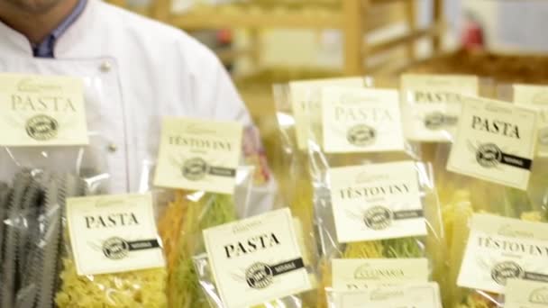 Chef-kok glimlacht naar camera - gedroogde pasta in pakketten - closeup - Video