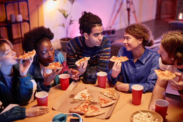 Visão de alto ângulo no grupo de jovens comendo pizza no estilo casa festa dos anos 80 - Foto, Imagem