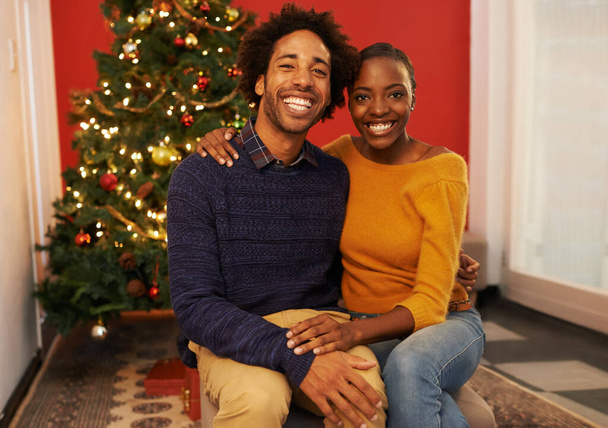Ζευγάρι, πορτρέτο και τις διακοπές των Χριστουγέννων στο δέντρο στο διαμέρισμα για γιορτή συγκόλλησης με διακόσμηση, σύνδεση ή φώτα. Άνδρας, γυναίκα και πρόσωπο στο σαλόνι για εορταστική περίοδο, δώρα ή γάμο. - Φωτογραφία, εικόνα