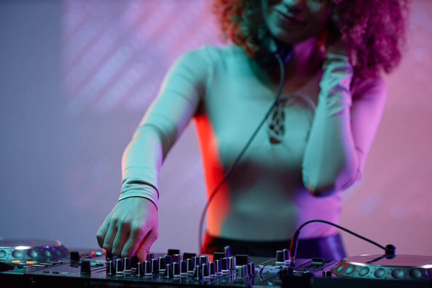 Primo piano di giovane donna come DJ fare musica al giradischi in luce al neon - Foto, immagini