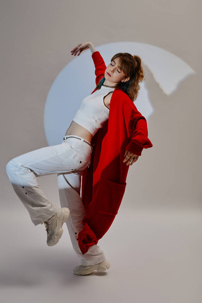 Vertikální obraz mladé dívky v červené těší její tanec proti bílému pozadí - Fotografie, Obrázek