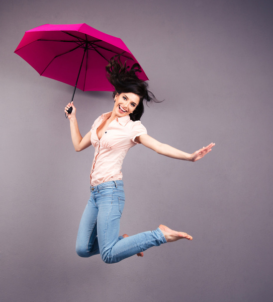 Happy young woman jumping with umbrella - Valokuva, kuva