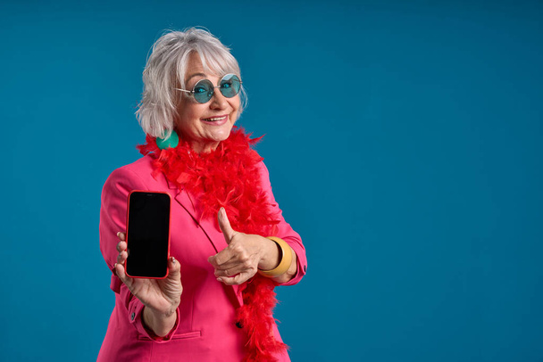 Technikaffiner Senior zeigt Smartphone und drückt Daumen hoch - Foto, Bild