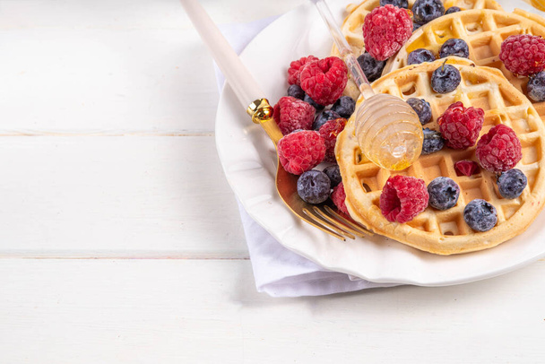 Homemade belgian waffles with summer berries and honey on white wooden table, Delicious brunch or breakfast belgian waffles - Photo, Image