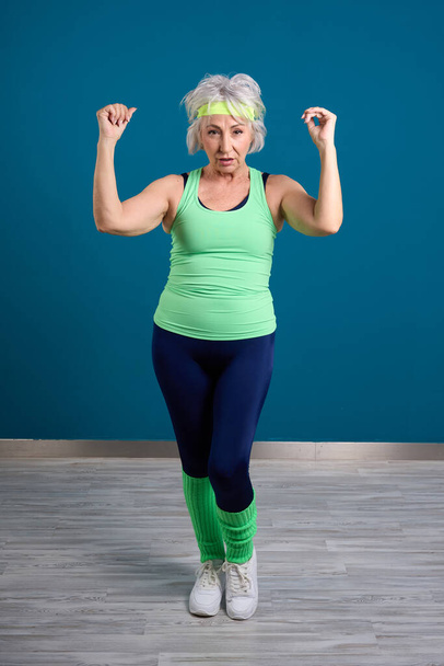 Ηλικιωμένη γυναίκα με φόρμες γυμναστικής με μπλε φόντο - Φωτογραφία, εικόνα