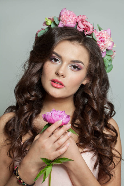 Vonzó női modell virágos nyári koszorúval a haján. fiatal nő tiszta bőr és hullámos frizura fehér háttér - Fotó, kép
