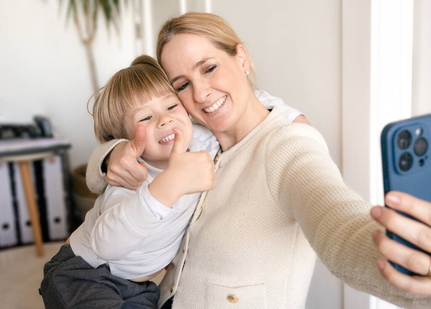 Porträt einer liebenden Mutter, die ein Selfie mit ihrem kleinen Sohn macht, Mutter, die ein Foto mit dem Smartphone macht - Foto, Bild