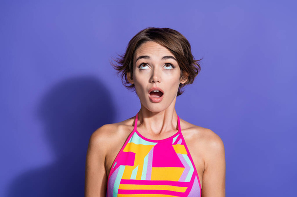 Photo of impressed shocked girl wear trendy vivid clothes look up banner empty space isolated on purple color background. - Фото, изображение