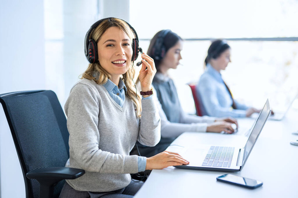 Vrouw operator agent met headsets en haar team werken in een call center klantenservice - Foto, afbeelding