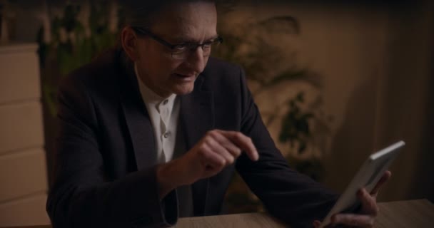 Üst düzey erkek yönetici, ofiste geç saatlere kadar çalışırken dijital tabletle ilgili video konferansı sırasında açıklama yapıyor - Video, Çekim