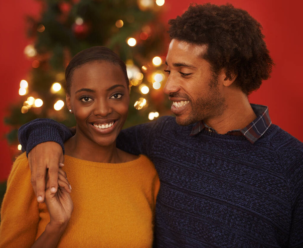 クリスマス, 木と自宅で愛とブラックカップルの肖像画 休暇や幸せと休暇に抱擁. お祝い,イベント,人々は一緒に祝うためにケアとサポートや興奮を受け入れます. - 写真・画像