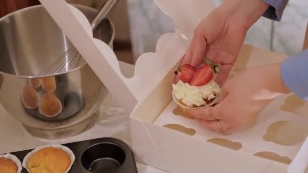 Een vrouwelijke banketbakker die cupcakes in een doos verpakt. Thuis bakken, kleine bedrijven, milieuvriendelijke productie, glutenvrij, suikervrij, bevorderen van gezonde eetgewoonten. - Video