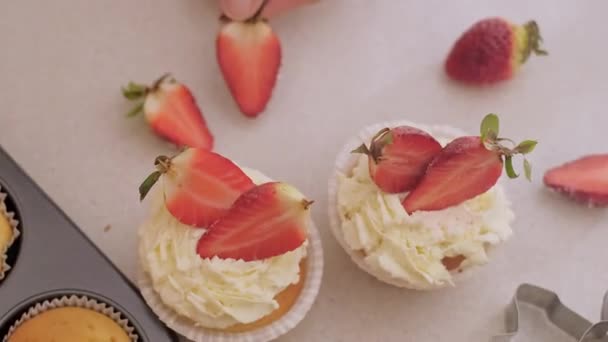 Une pâtissière décore des cupcakes avec des fruits, des cupcakes aux fraises, de la pâtisserie maison, une petite entreprise, une production respectueuse de l'environnement, des produits sans gluten, une alimentation saine et sans sucre. - Séquence, vidéo