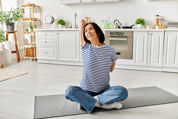 Donna in accogliente biancheria da casa praticare yoga su un tappeto in cucina. - Foto, immagini