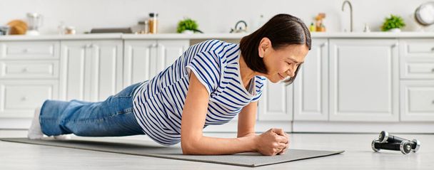 Eine reife Frau in Hausbekleidung praktiziert Yoga auf einer Küchenmatte. - Foto, Bild