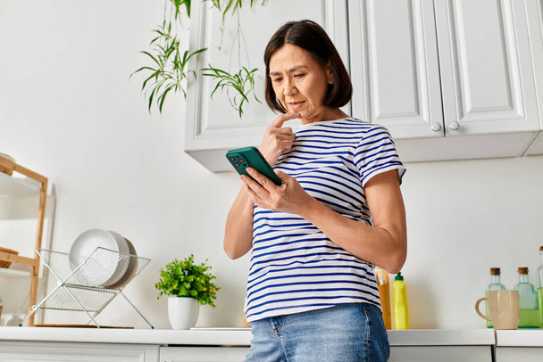 Vrouw in gezellige huiskledij houdt zich bezig met tablet in moderne keuken. - Foto, afbeelding