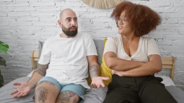 Verärgertes schönes Paar sitzt zusammen auf dem Bett im Schlafzimmer und streitet über Beziehungsprobleme - Filmmaterial, Video