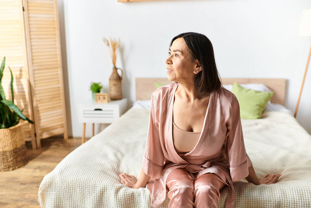 Een volwassen vrouw in gezellige huiskleding ontspannen op een bed in een serene kamer. - Foto, afbeelding