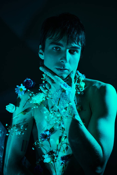Ein junger Mann posiert, ohne Hemd und mit zarten Blumen geschmückt - Foto, Bild