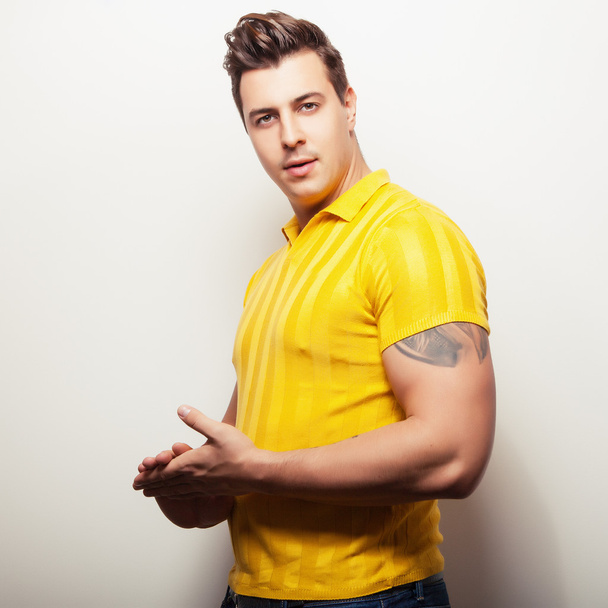 Elegant young handsome man in bright yellow t-shirt. Studio fashion portrait. - Foto, Imagen