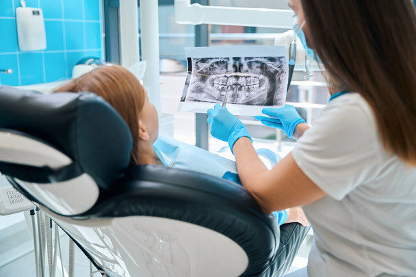 Стоматолог с молодым пациентом осматривает фотографию зубов, современное оборудование в стоматологической клинике - Фото, изображение