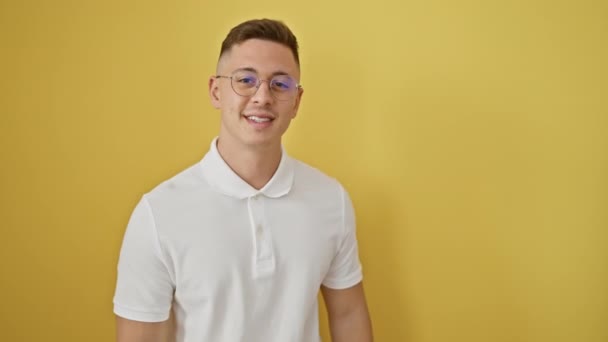 Attraktiver junger hispanischer Mann, der großes Selbstwertgefühl zeigt, indem er selbstbewusst auf sich selbst zeigt, eine große Brille auf isoliertem gelben Hintergrund trägt und dabei ein stolzes und glückliches Lächeln trägt. - Filmmaterial, Video