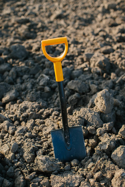 A shovel on the background of a plowed field. Treasure hunting and archeology concept. - Photo, Image