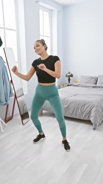 Zářící úsměv půvabný mladý, sebevědomý hispánský žena těší její rytmický tanec cvičení v útulném interiéru svého pokoje, objímající zdravý, aktivní životní styl. - Záběry, video
