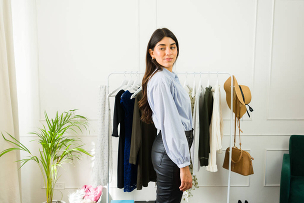 Jungunternehmerin steht neben Kleiderständer in Boutique - Foto, Bild
