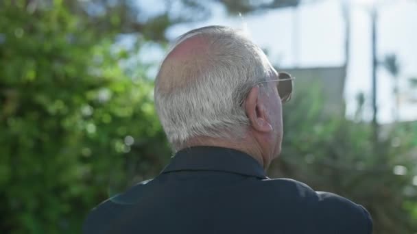 Lässiges Porträt eines reiferen weißhaarigen älteren Mannes, der rückwärts steht und auf den üppig grünen Park blickt; Rückansicht zeigt, ein Spiegelbild der Reise des Lebens, die von Natur durchdrungen ist - Filmmaterial, Video