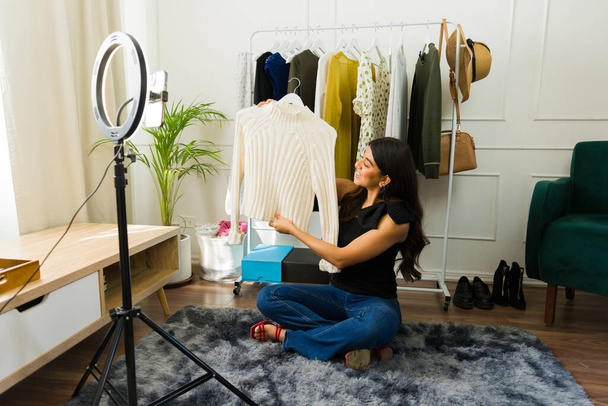 Mujer joven muestra ropa mientras filma para su vlog de moda en casa - Foto, imagen