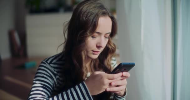 jong aantrekkelijk vrouw brunette chatten op mobiele telefoon terwijl dag dromen thuis - Video