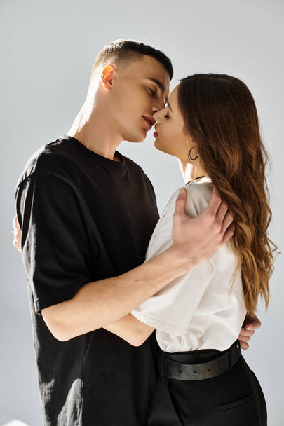 Un jeune homme et une jeune femme s'embrassent intimement dans un studio avec un fond gris. - Photo, image