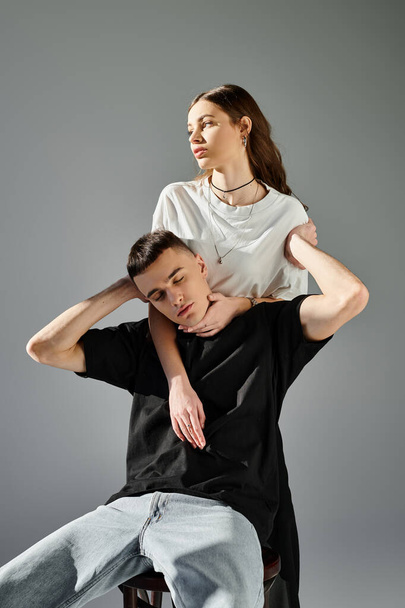 Un hombre se equilibra sobre los hombros de una mujer en un estudio con un fondo gris. - Foto, Imagen