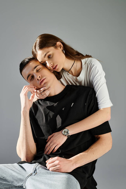 Un jeune homme équilibre précairement sur une épaule de femme dans un studio avec un fond gris. - Photo, image