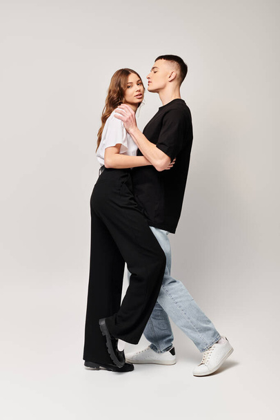 Egy fiatal szerelmespár táncol együtt szenvedéllyel egy stúdióban, szürke háttérrel.. - Fotó, kép